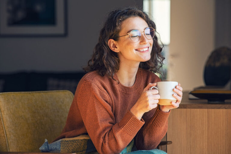 woman smiling while holding a mug